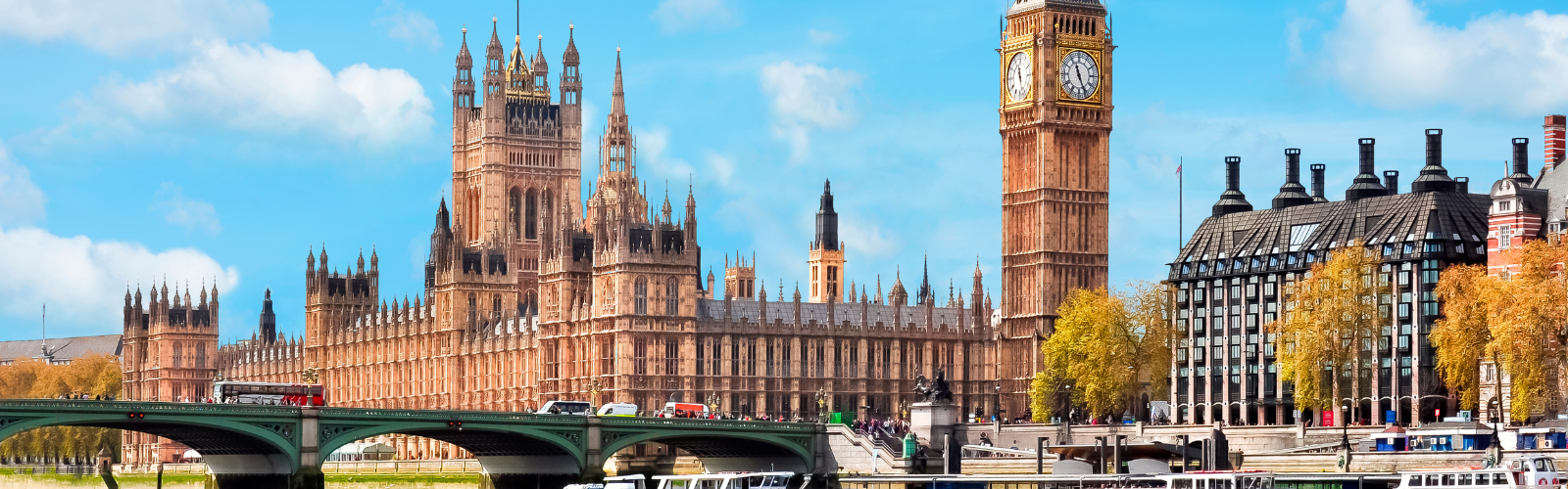 View of Big Ben and Parliament from the Thames riverbank. It is a bright and clear day.